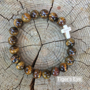 top view of the  Mens 'Thou Art With Me' Natural Stone Bead Cross Bracelets Tiger's Eye against the cut surface of a log
