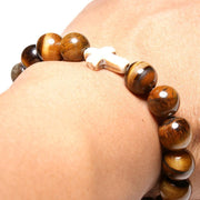 Close-up view of the  Mens 'Thou Art With Me' Natural Stone Bead Cross Bracelets Tiger Eye on an arm